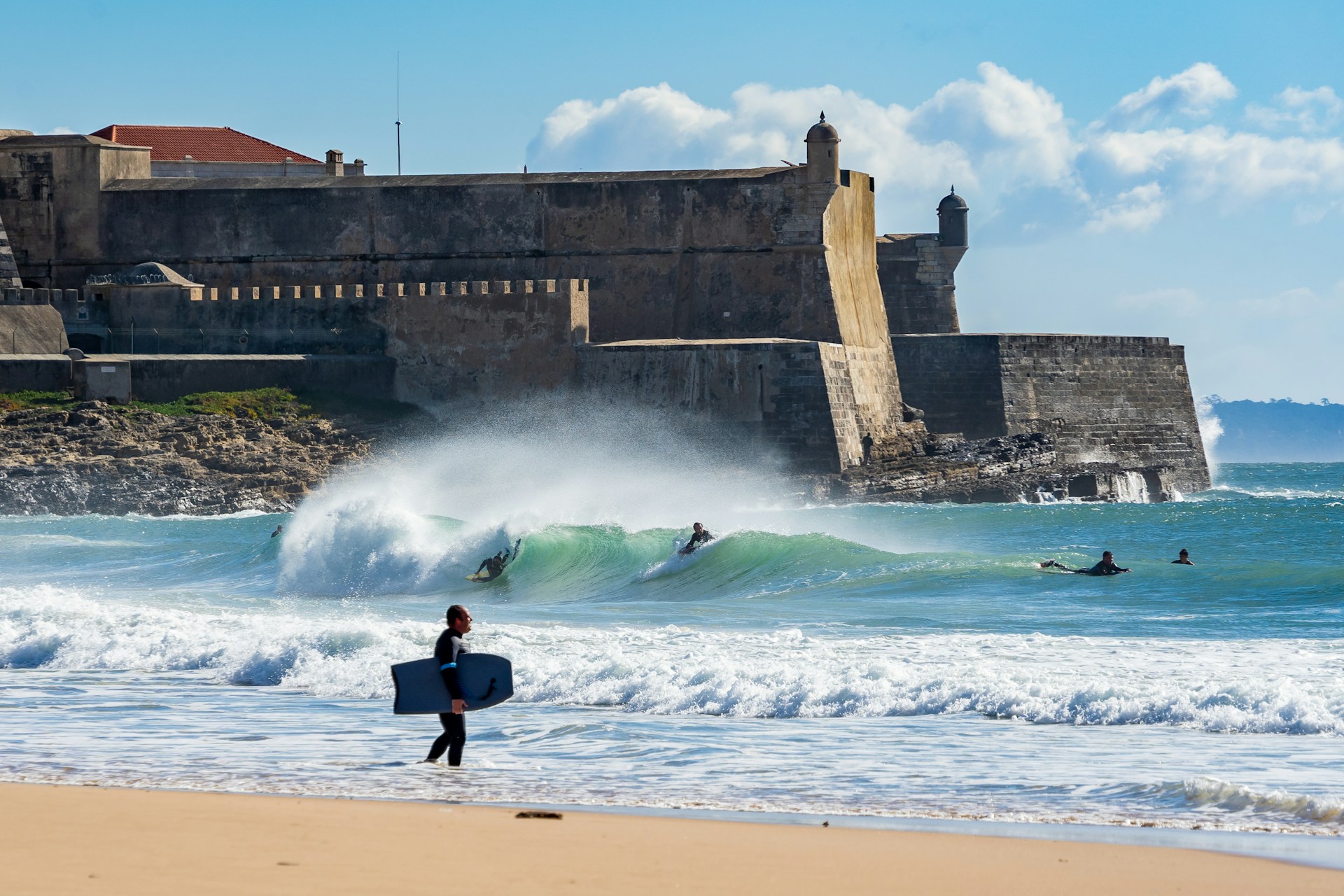 Hombre sosteniendo su tabla de bodyboarding caminando hacia el mar.